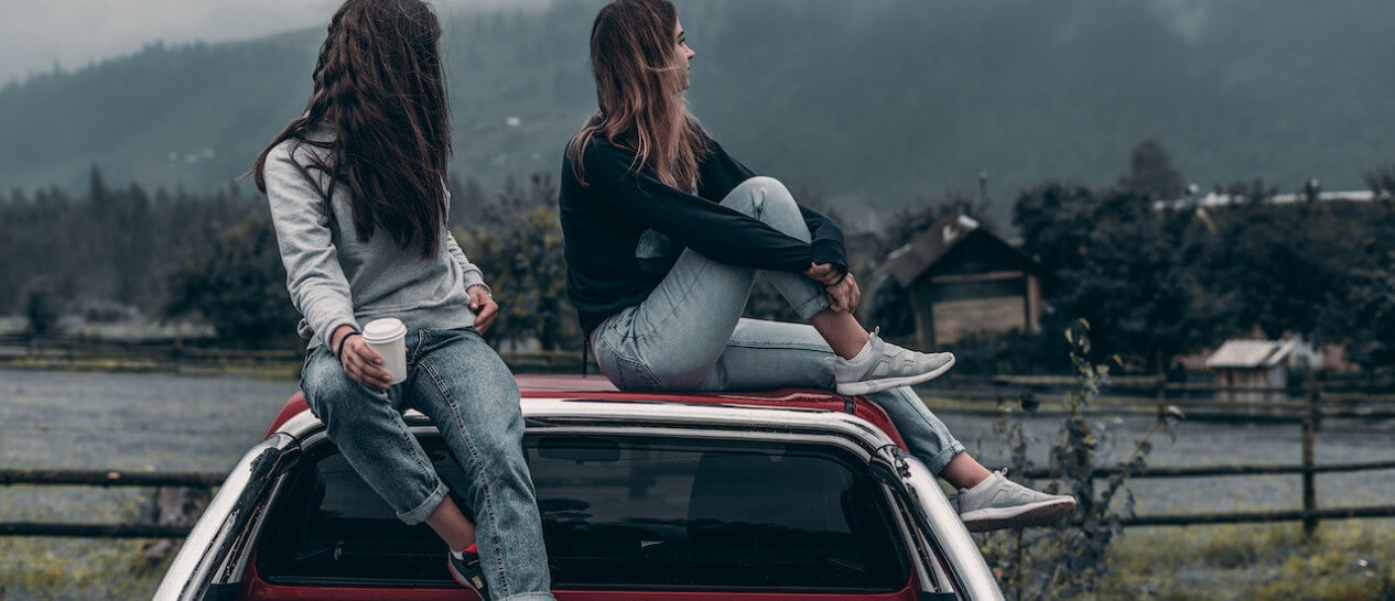 2 people sitting on a car and chilling