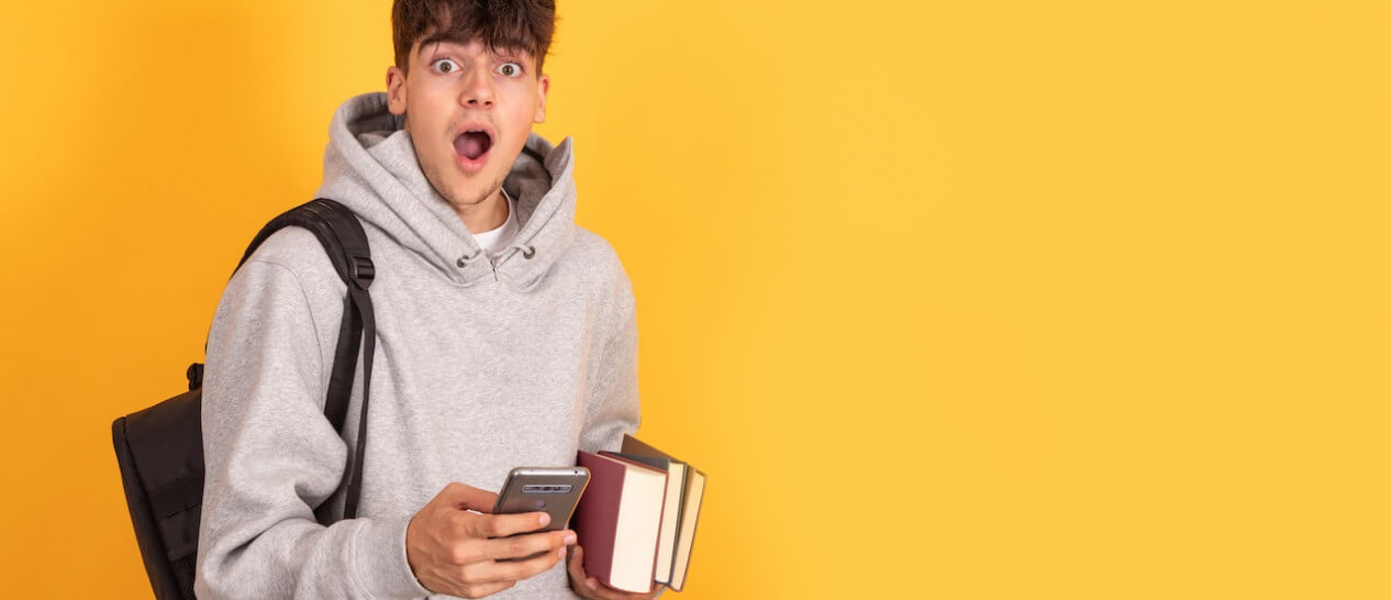student holds smartphone looking astonished