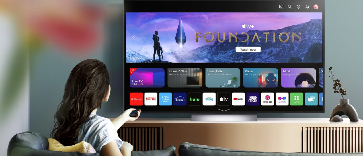 young woman sits on couch watching lg tv