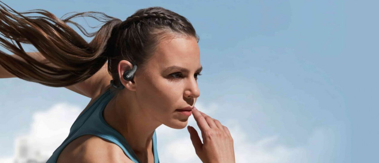 young woman wears open-ear buds