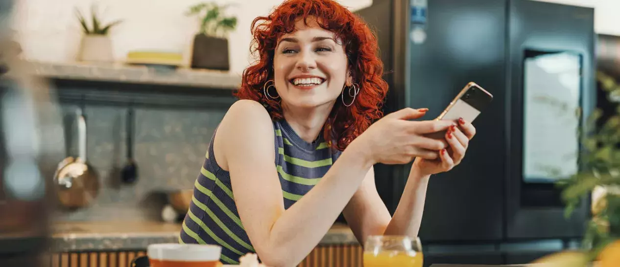 Μία γυναίκα απολαμβάνει το νέο της budget smartphone που αγόρασε από τον ΓΕΡΜΑΝΟ