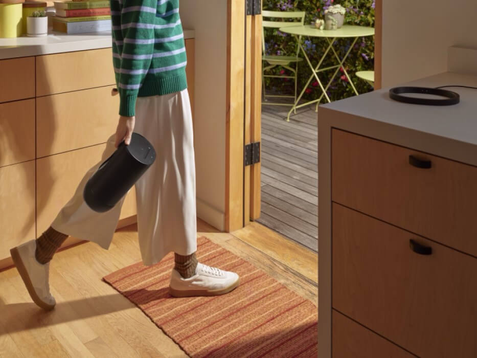 guy walking from room to room with sonos move 2 in hand
