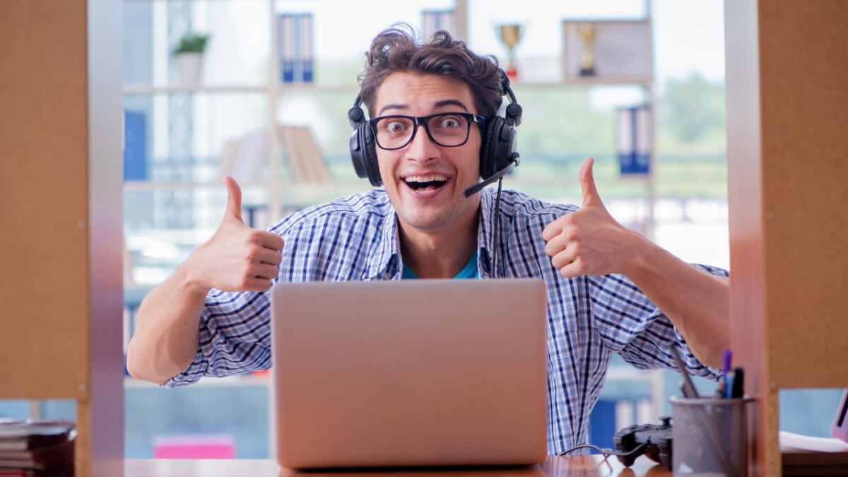 young man gives thumbs up in front of laptop