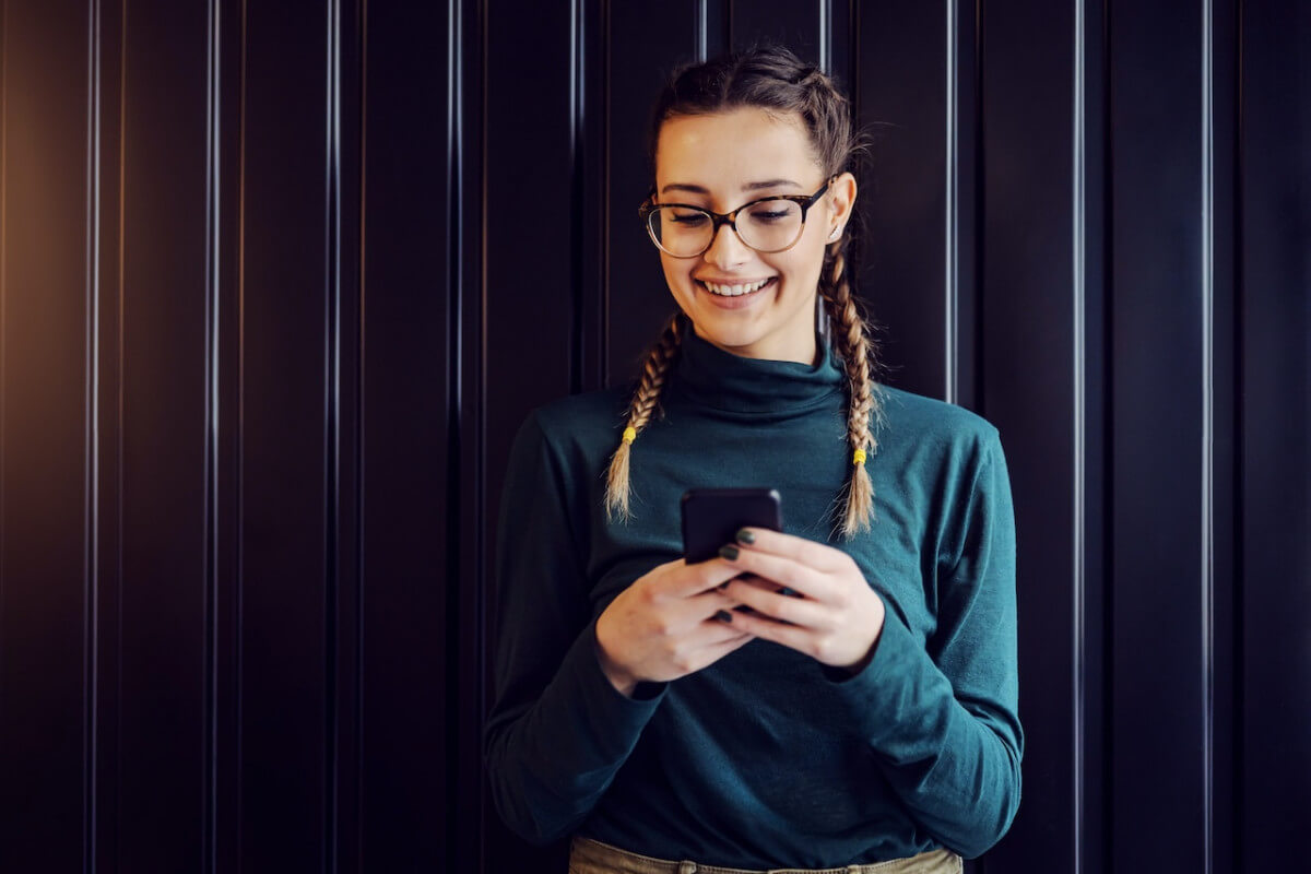 young woman smiles typing on smartphone