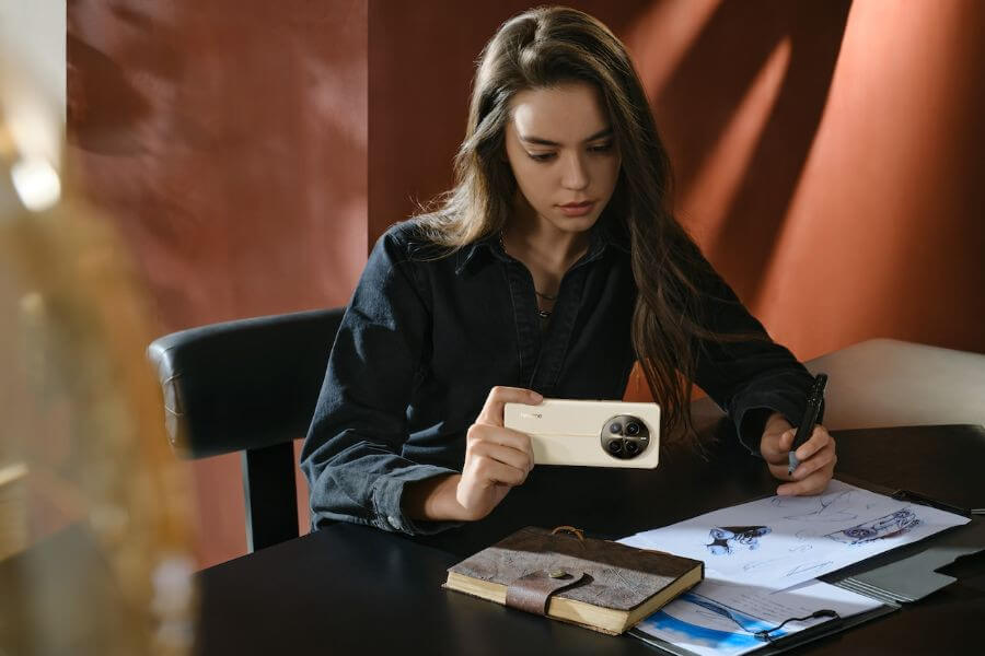 young woman sits at desk with realme 12 pro smartphone