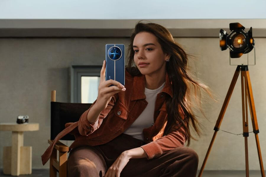 young woman sits at chair with realme 12 pro smartphone