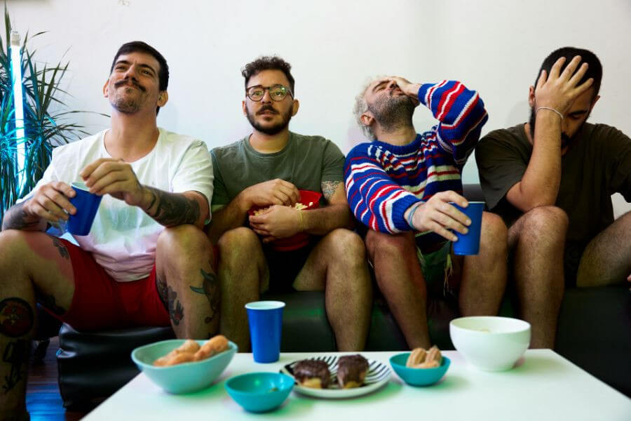 4 guys sitting on couch watching TV