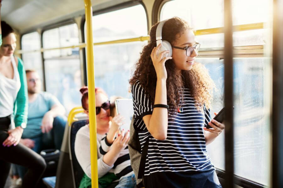 teenager with white headphones in bus