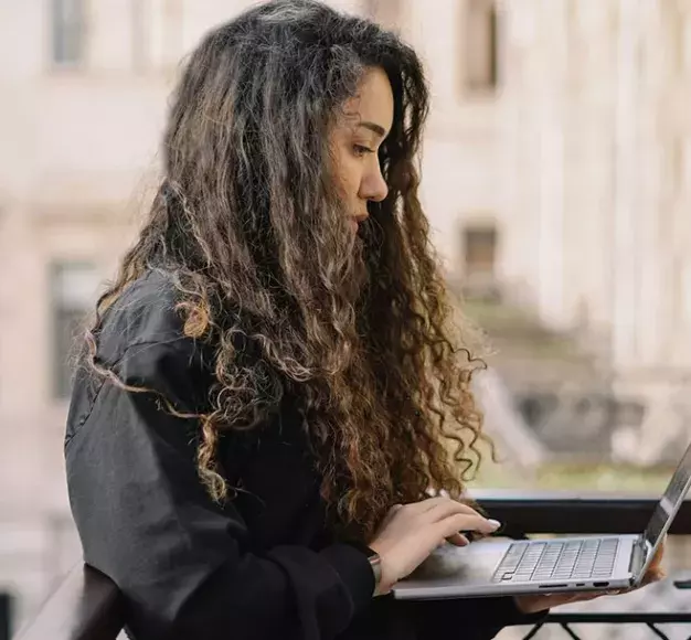 Μία γυναίκα χρησιμοποιεί το νέο της laptop που πήρε από τον ΓΕΡΜΑΝΟ τη Black Friday 2025 στο μπαλ...