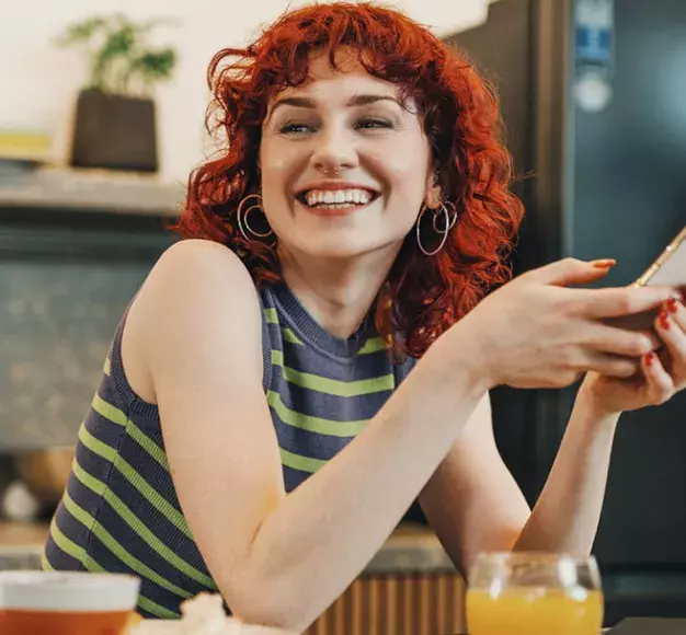 Μία γυναίκα απολαμβάνει το νέο της budget smartphone που αγόρασε από τον ΓΕΡΜΑΝΟ