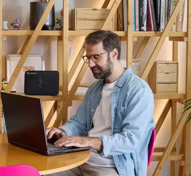 Ένας άνδρας κάνει δουλειά στο laptop του απολαμβάνοντας τα πλεονεκτήματα μίας σύνδεσης COSMOTE